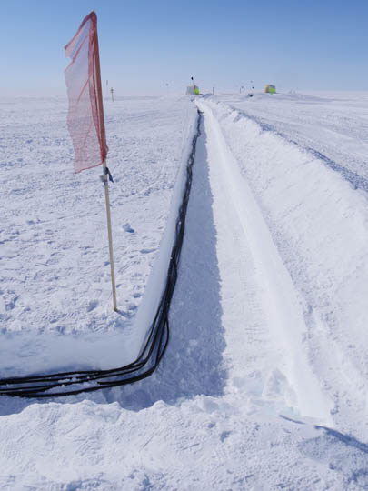 In order to protect the cables from passing vehicles, the cables are bundled up and placed in shallow trenches to be covered with snow.